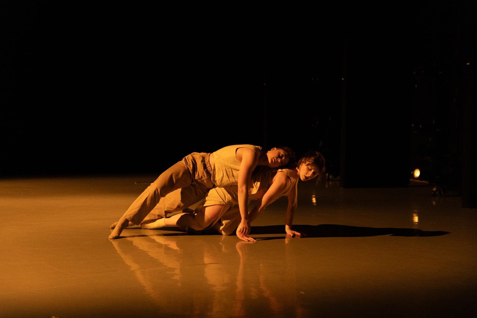 Two Aslin Projects dancers low to the floor under warm light, APAP 2026